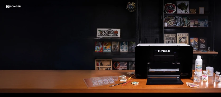 The Longer ePrint dual-head UV printer in a workshop, surrounded by the phone cases, bottles and tags it decorates