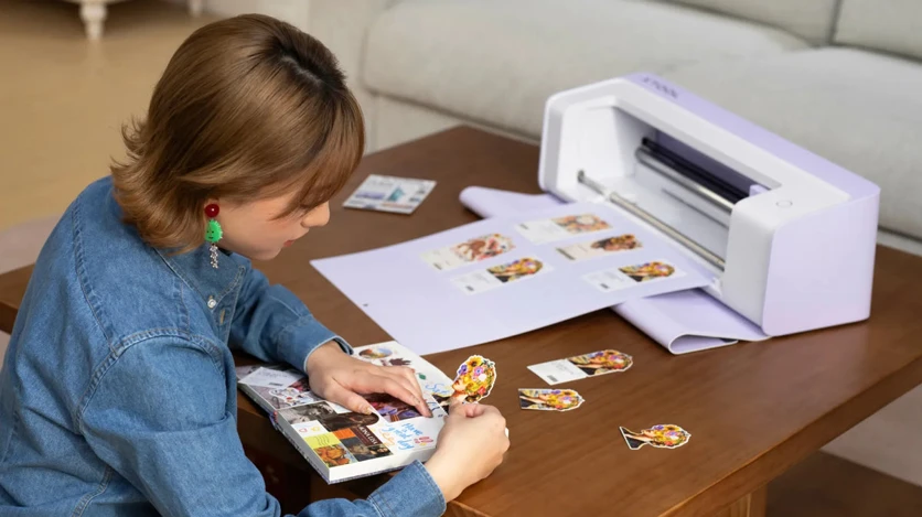 xTool C1 cutting printed artwork while a crafter arranges cutouts in a journal