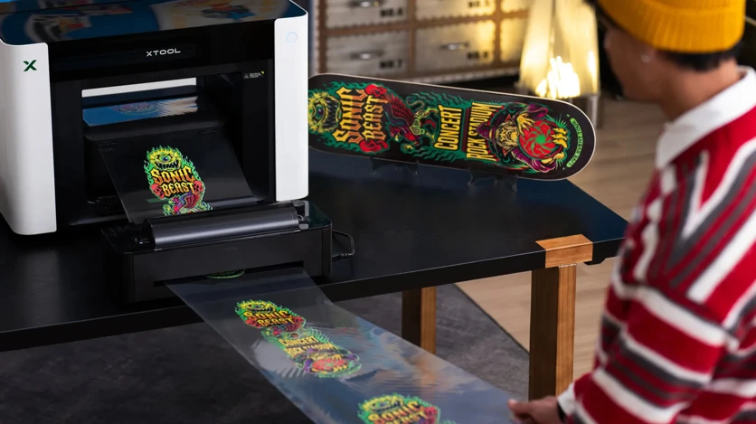The xTool O1 Omni printing a UV DTF transfer onto a skateboard deck: one of four print methods on the top edition